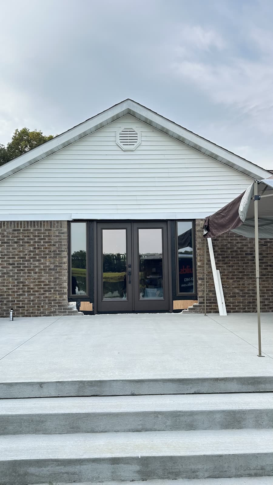 Dark bronze double patio doors installed on the gable end of a brick ranch home