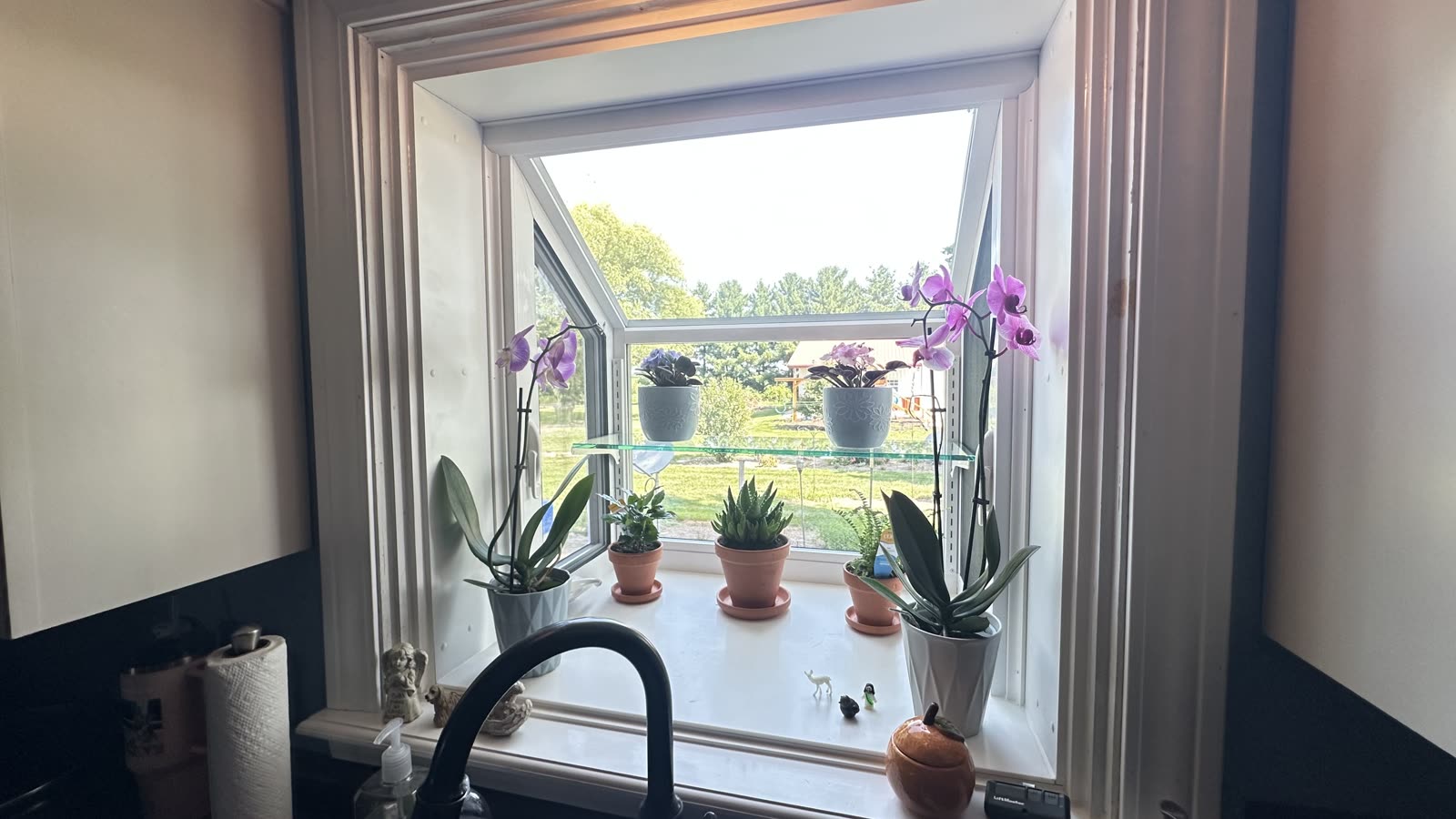 New white garden window above a kitchen sink with a glass plant shelf