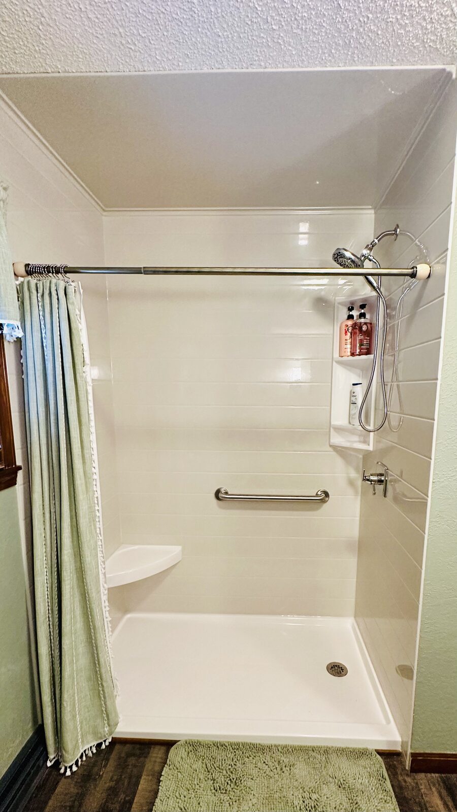 New white walk-in shower with corner seat, grab bar and low threshold base