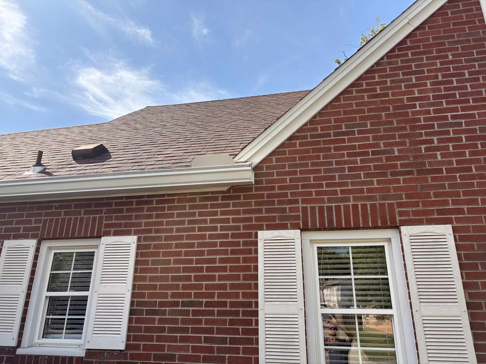 White seamless gutter and fascia detail on a brick home with shutters