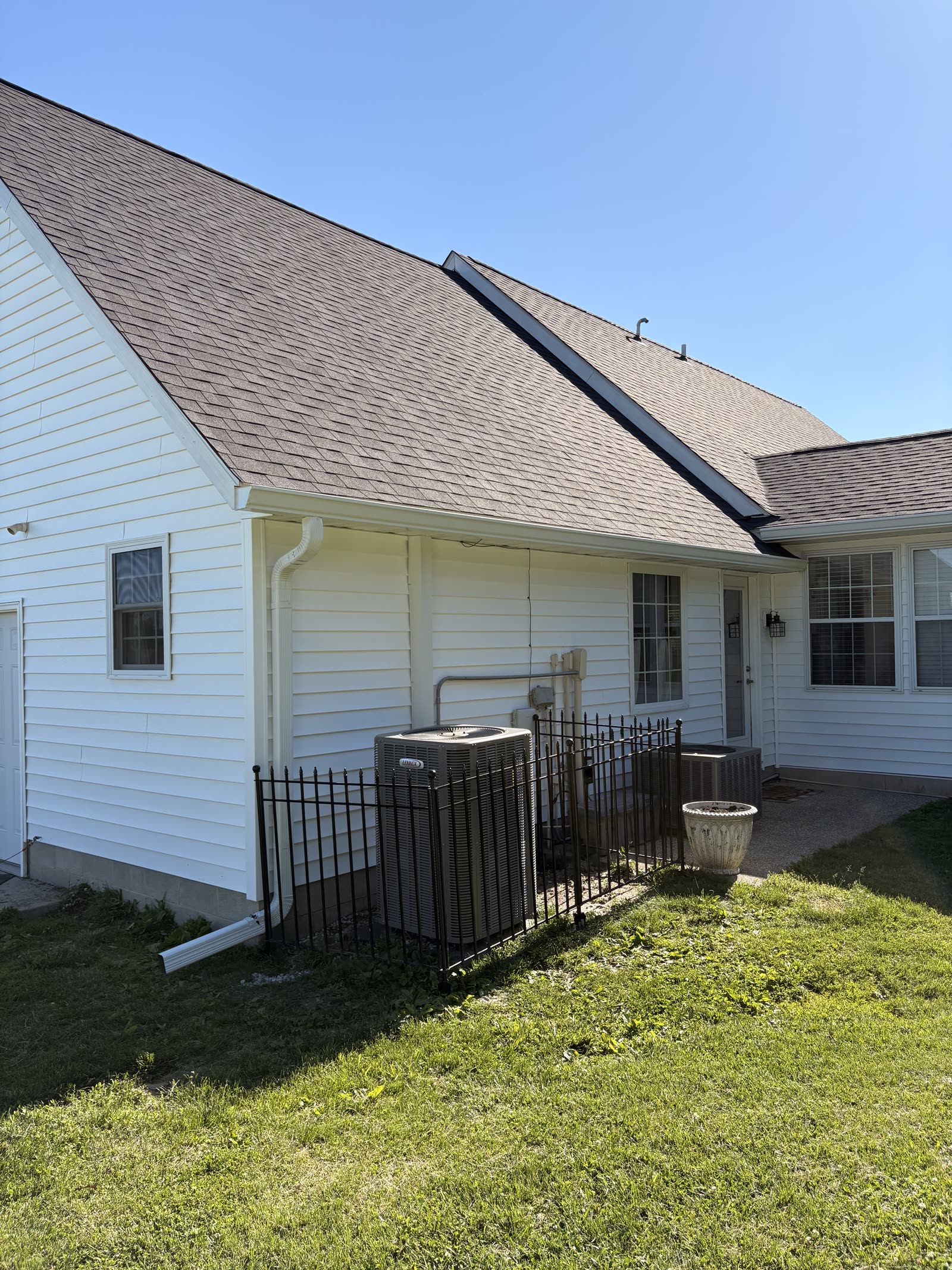 White seamless gutter with downspout carrying water away from a home's foundation