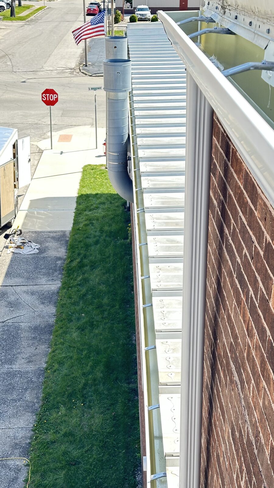 Long run of new white seamless gutter along a brick commercial building