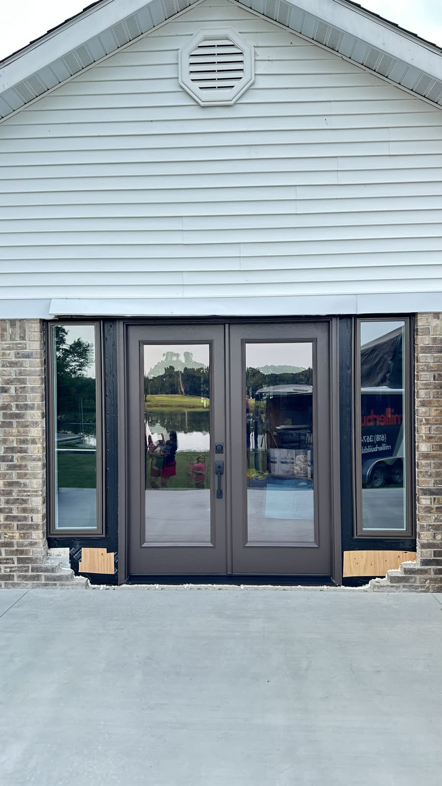 New bronze French patio doors with full-view glass and matching sidelites on a brick home