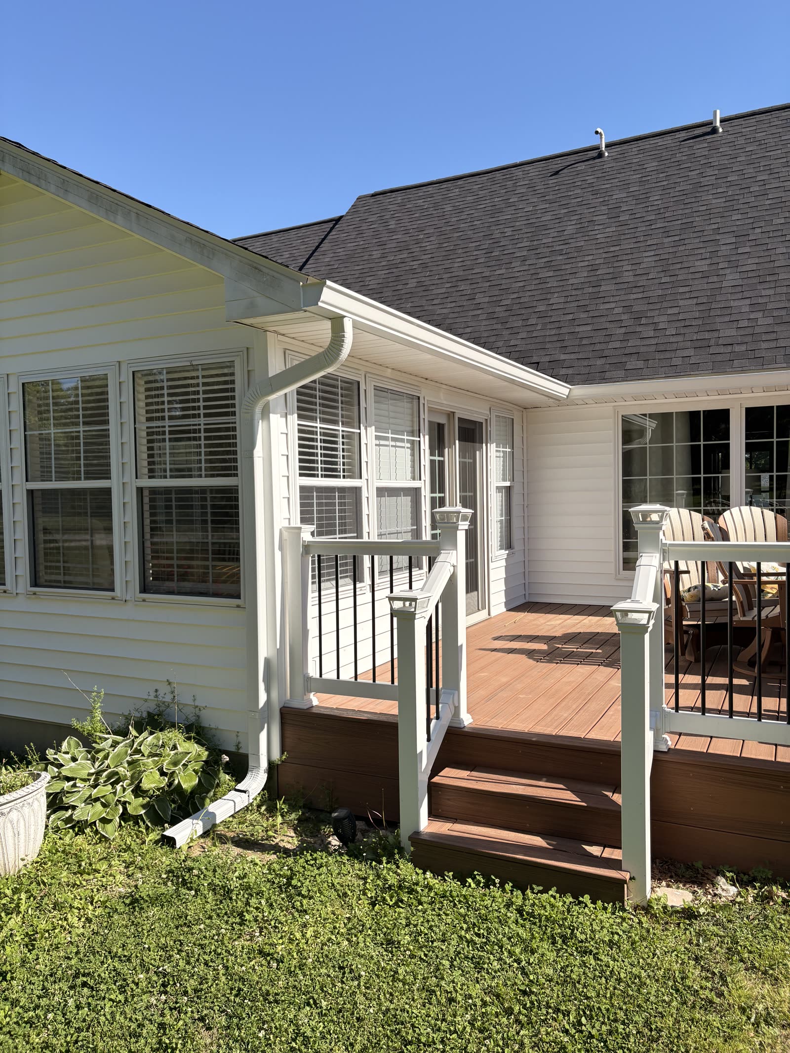 White seamless gutters running along the back roofline of a ranch home with a deck