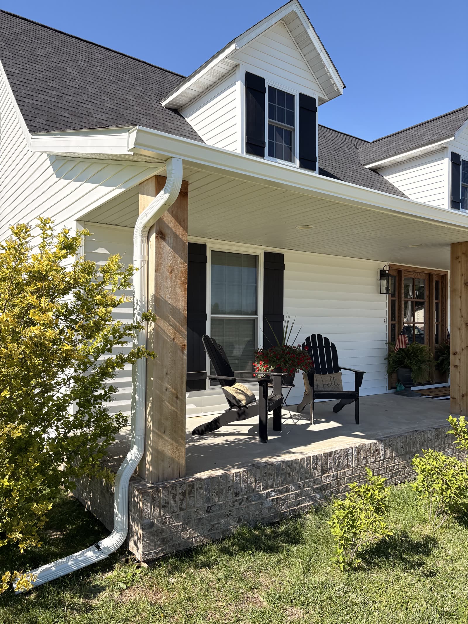 New white seamless gutter and downspout on the front porch of a white sided home