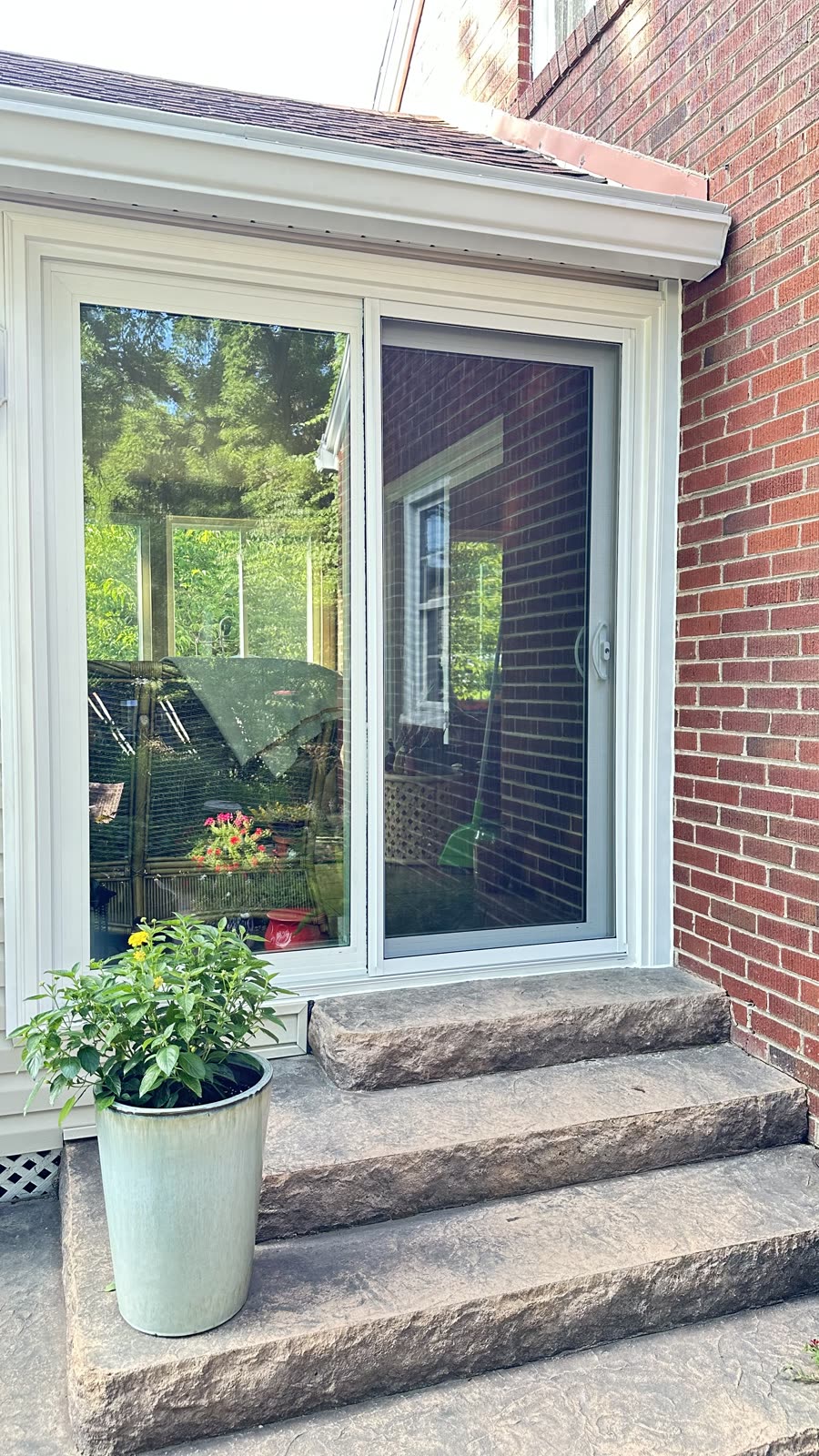 White vinyl sliding patio door installed above stone steps on a brick home